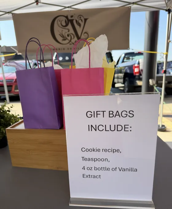 Purple, pink and yellow gift bags with tissue paper next to a sign listing what each gift bag includes
